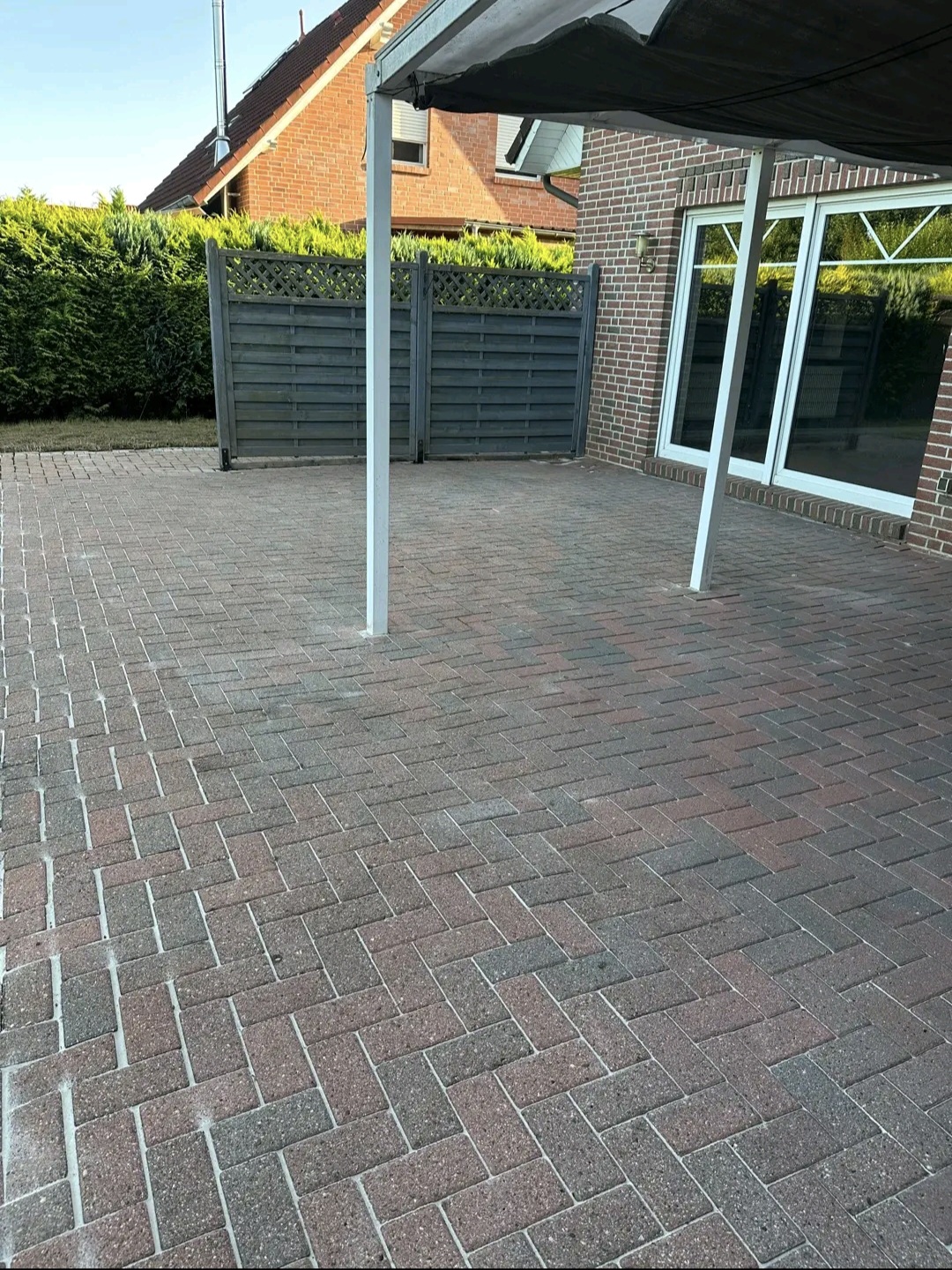 Gereinigte anthrazitfarbene Pflasterterrasse an einem Backsteinhaus