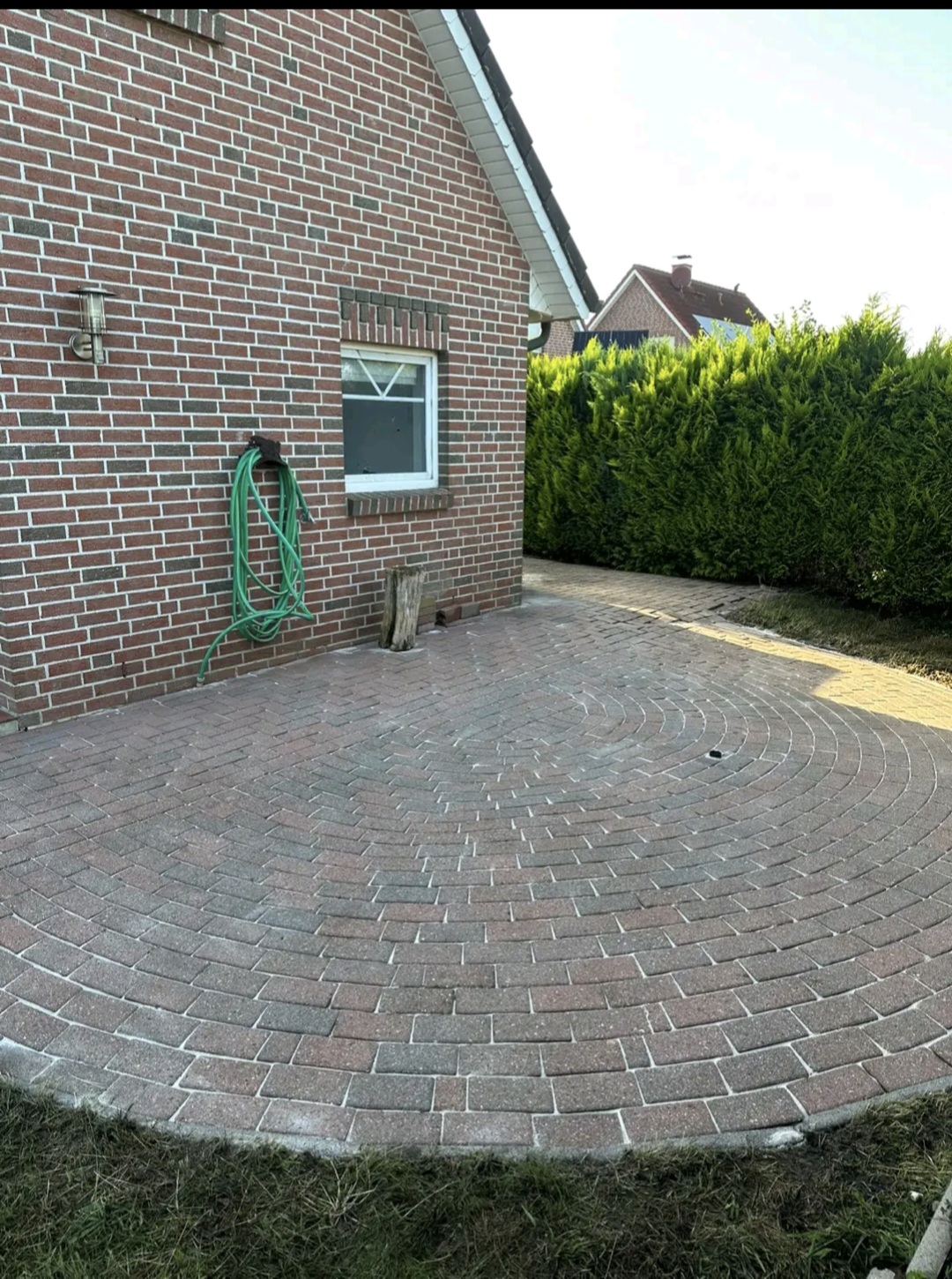 Gereinigte Terrasse mit rundem Pflastermuster an einem Backsteinhaus