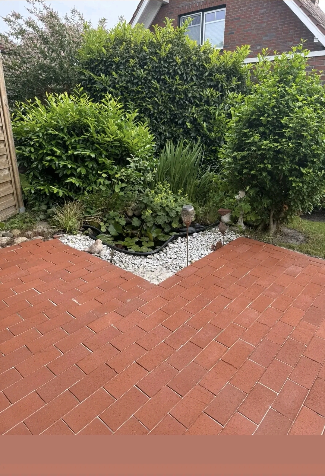 Frisch gereinigte rote Pflasterstein-Terrasse mit gepflegtem Garten – Nachher-Ergebnis von Rafo Reinigung